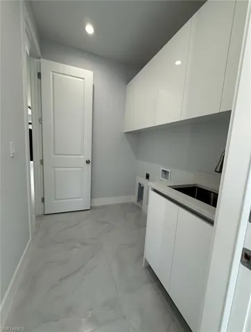 Clothes washing area featuring a sink, electric dryer hookup, marble finish floor, cabinet space, and hookup for a washing machine