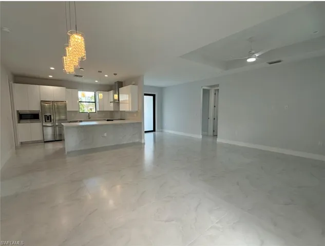 Kitchen with visible vents, range hood, stainless steel appliances, white cabinetry, and open floor plan