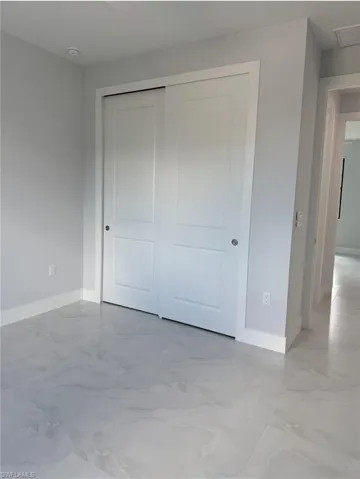 Unfurnished bedroom with marble finish floor, baseboards, and a closet