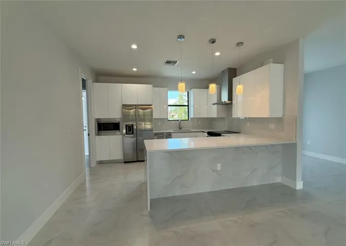 Kitchen with visible vents, modern cabinets, wall chimney exhaust hood, stainless steel appliances, and backsplash