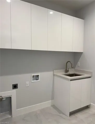 Laundry room featuring a sink, washer hookup, hookup for an electric dryer, marble finish floor, and cabinet space