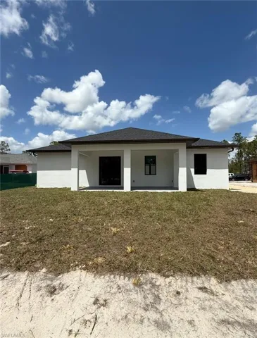Rear view of property featuring stucco siding and a lawn