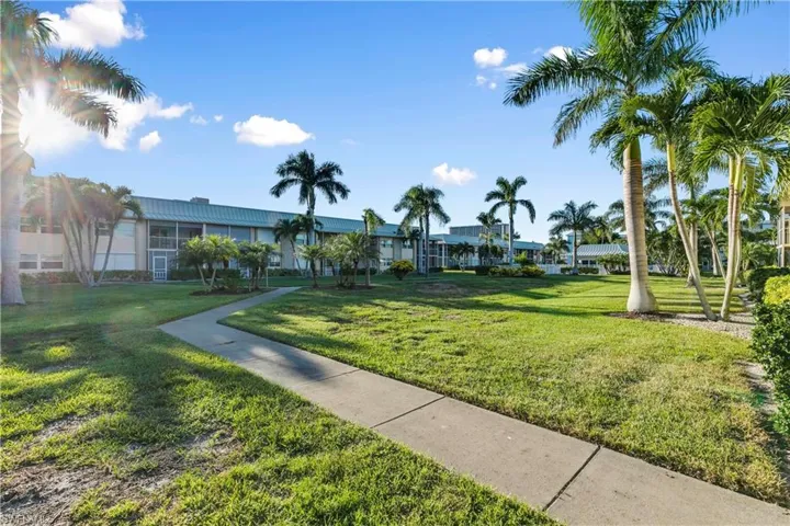 Walk to the pool surrounded by palm trees and green grass