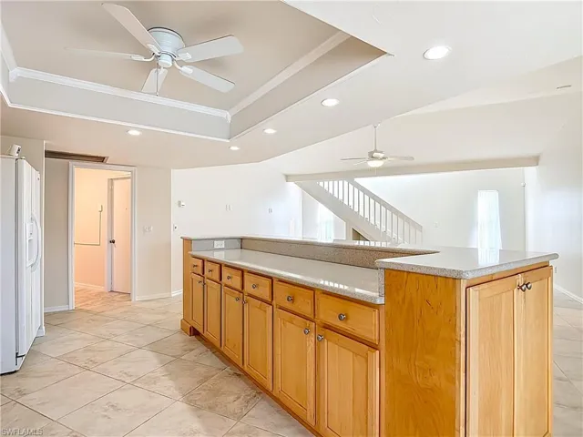 Kitchen with a raised ceiling, white fridge with ice dispenser, recessed lighting, crown molding, and a ceiling fan