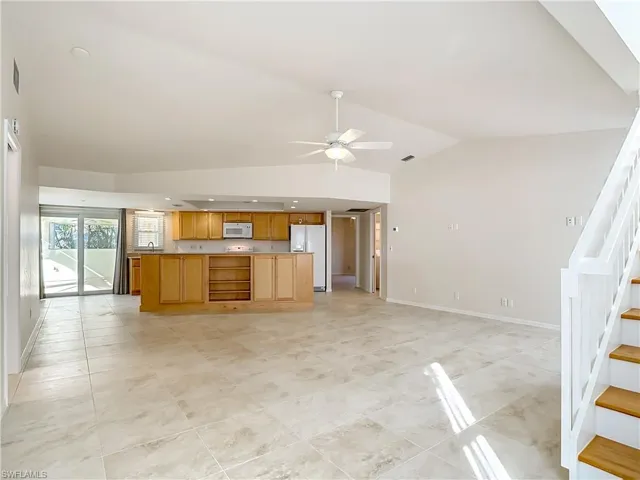 Kitchen featuring open floor plan, white appliances, lofted ceiling, open shelves, and light countertops