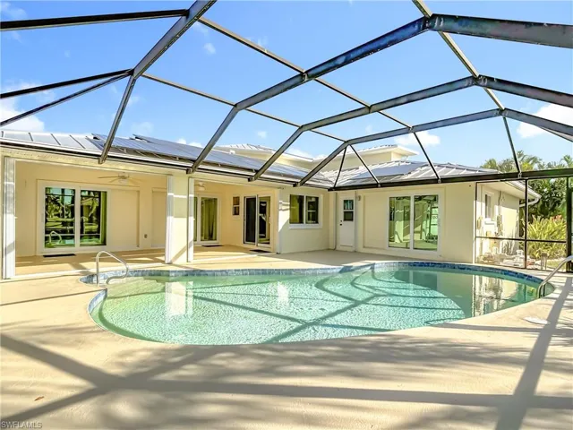 Swimming pool with glass enclosure, a sunroom, a ceiling fan, and a patio