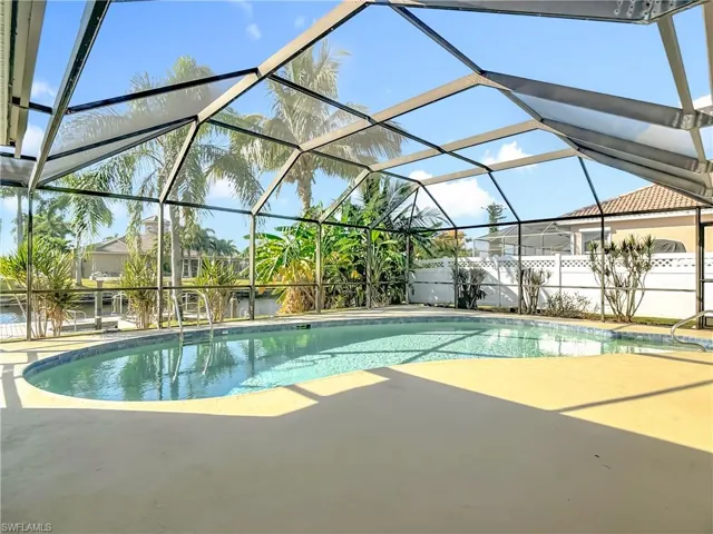 View of pool featuring a sunroom, glass enclosure, and a patio area