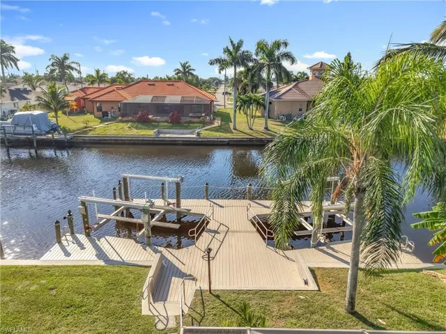 Dock area featuring a lawn, a water view, a residential view, and boat lift