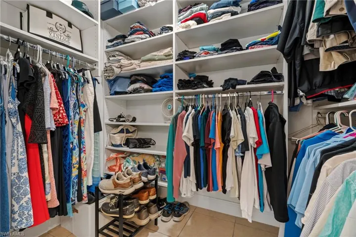 Custom closet system featuring multiple hanging rods, integrated shelving, and tiled flooring
