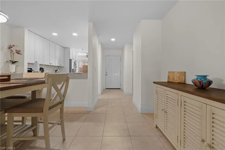 Hallway with light-colored tile flooring leading to a white entry door