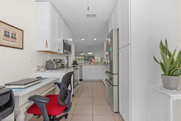 Galley kitchen featuring white cabinetry, stainless steel appliances, light-toned countertops, and recessed lighting