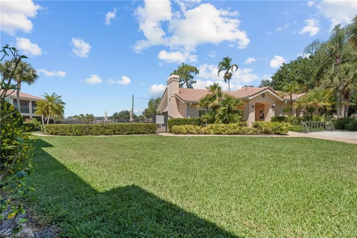 Expansive green lawn bordering the pool with a tiled roof, stucco exterior, and mature palm trees