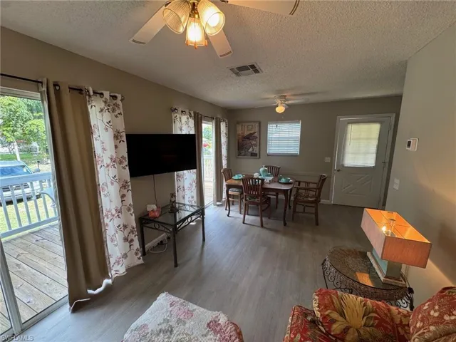 Dining space with wood finished floors, a textured ceiling, and a ceiling fan