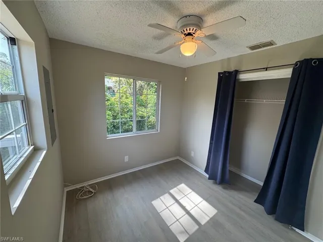 Unfurnished bedroom featuring light wood-style floors, a ceiling fan, a textured ceiling, and electric panel