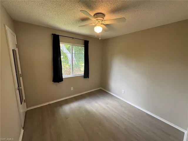 Empty room featuring light wood-style flooring, a textured ceiling, and a ceiling fan