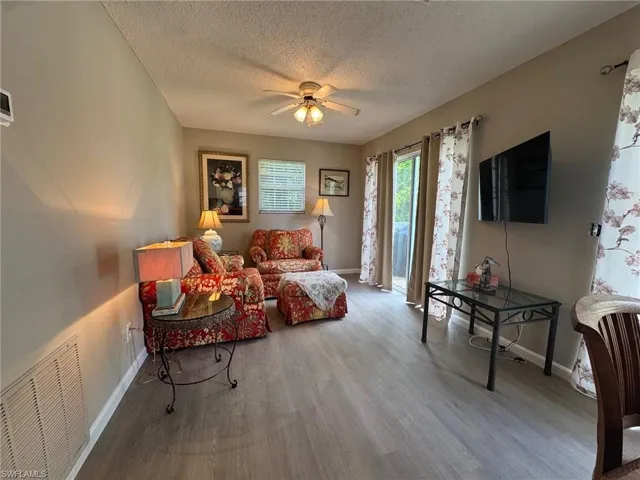 Living area featuring wood finished floors, a textured ceiling, and ceiling fan