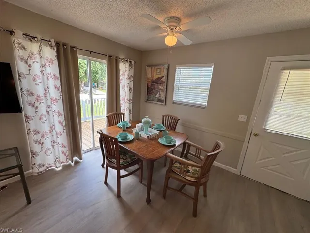 Dining space with light wood finished floors, a textured ceiling, and a ceiling fan