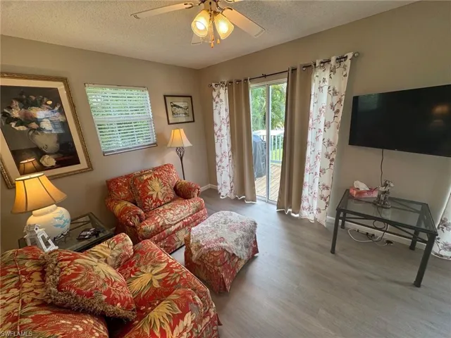 Living area featuring wood finished floors, a textured ceiling, and ceiling fan