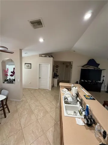 Kitchen with lofted ceiling, light countertops, light tile patterned floors, open floor plan, and recessed lighting