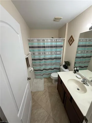Bathroom featuring vanity, a shower with shower curtain, and light tile patterned flooring