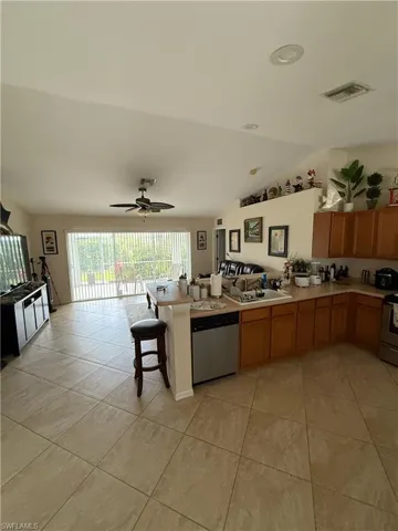 Kitchen featuring a peninsula, vaulted ceiling, light countertops, stainless steel appliances, and light tile patterned floors
