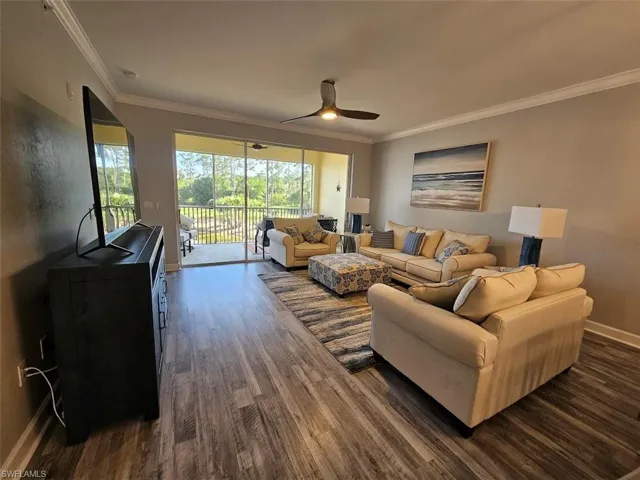 Living area with ornamental molding, ceiling fan, dark wood-style floors, and baseboards