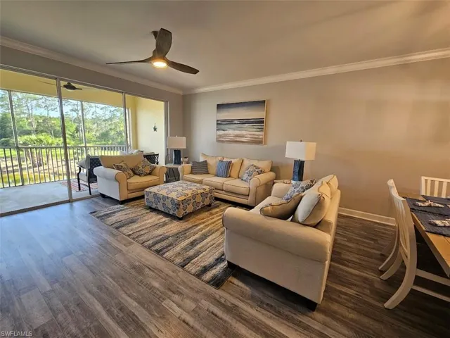 Living room with crown molding, ceiling fan, wood finished floors, and baseboards