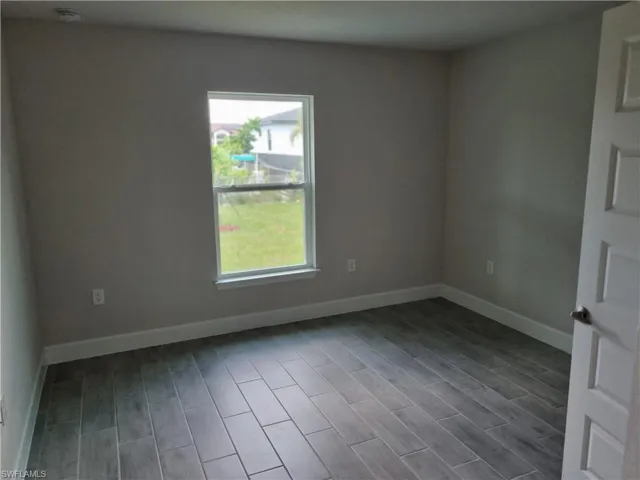 Empty room with baseboards, dark wood finished floors, and a smoke detector