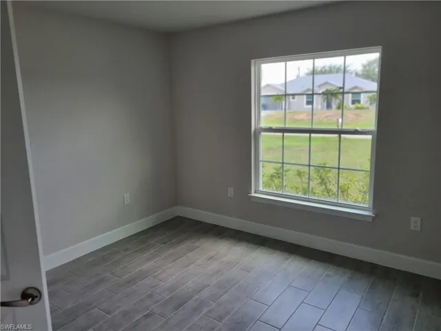 Spare room featuring plenty of natural light, baseboards, and dark wood-type flooring