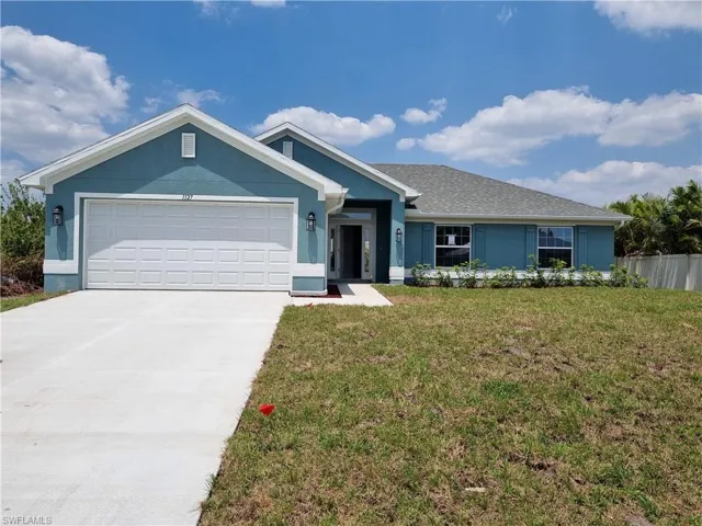 Ranch-style house featuring an attached garage, a front lawn, driveway, and stucco siding