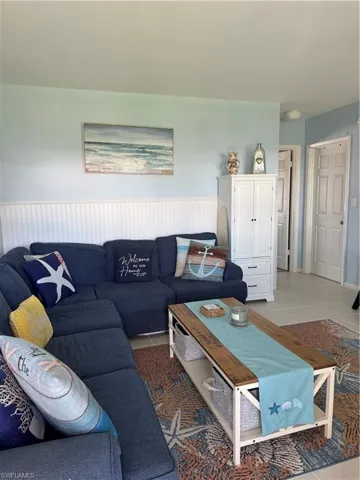 Living area featuring light tile patterned floors and a wainscoted wall