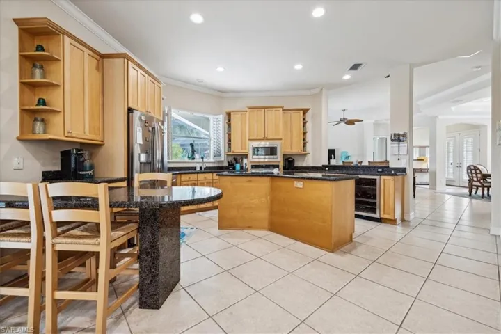 Kitchen featuring appliances with stainless steel finishes, kitchen peninsula, a kitchen island, crown molding, and beverage cooler
