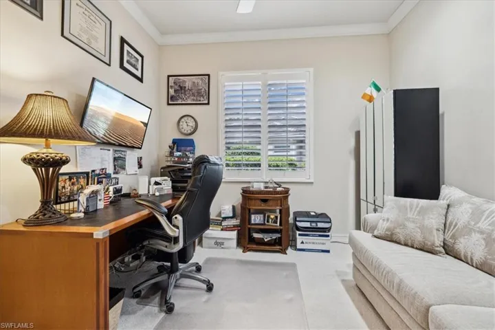 Carpeted office space featuring crown molding