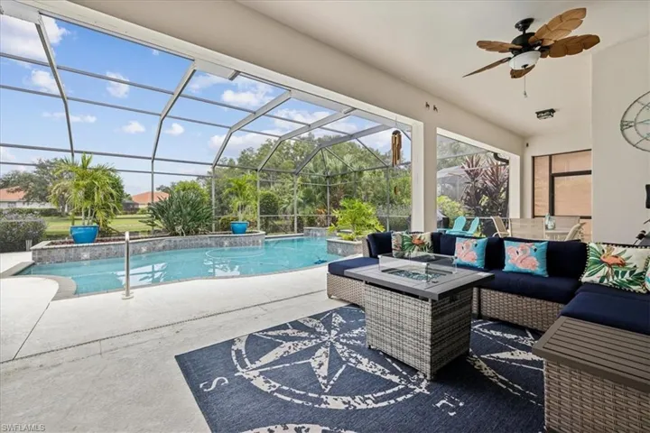View of swimming pool featuring a patio, ceiling fan, glass enclosure, and an outdoor hangout area