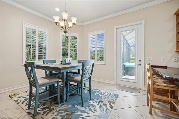 Dining space with light tile patterned floors, a notable chandelier, crown molding, and a wealth of natural light