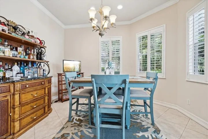 Tiled dining space with a chandelier and crown molding