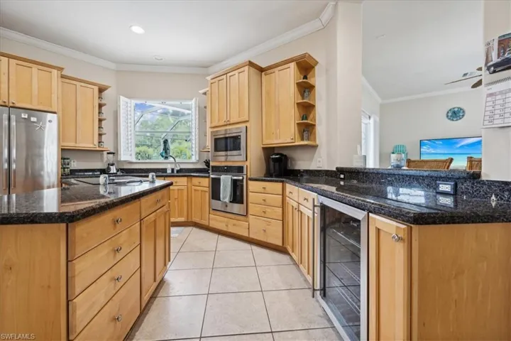 Kitchen featuring light tile patterned floors, kitchen peninsula, beverage cooler, stainless steel appliances, and light brown cabinetry