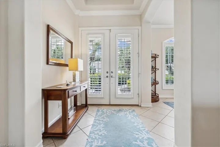 Tiled entryway with ornamental molding, french doors, and a healthy amount of sunlight