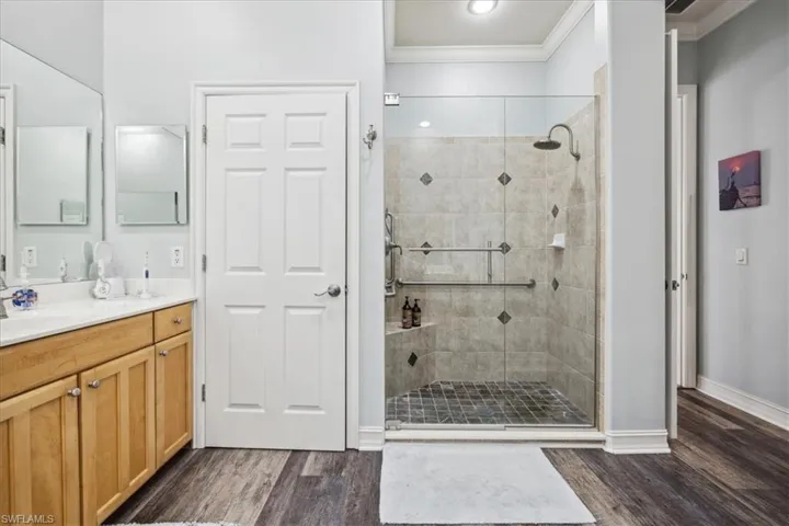 Bathroom with wood-type flooring, crown molding, vanity, and an enclosed shower