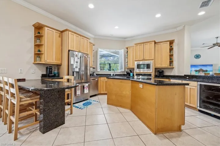 Kitchen with appliances with stainless steel finishes, beverage cooler, ceiling fan, and kitchen peninsula