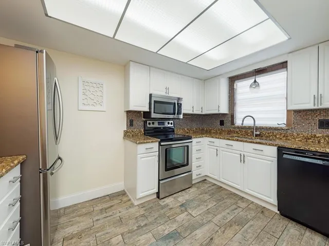 Kitchen featuring stainless steel appliances, tasteful backsplash, light wood finished floors, and a sink