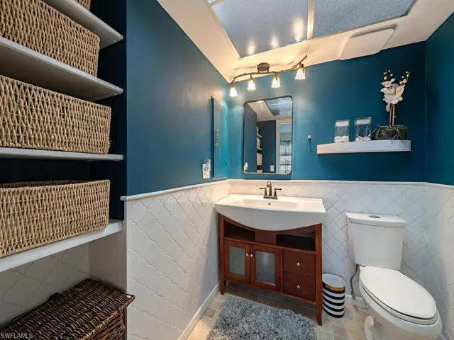 Bathroom with toilet, tile patterned flooring, a wainscoted wall, and vanity