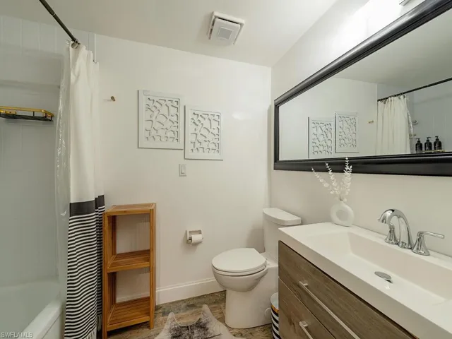 Full bathroom featuring visible vents, baseboards, toilet, shower / bathtub combination with curtain, and vanity