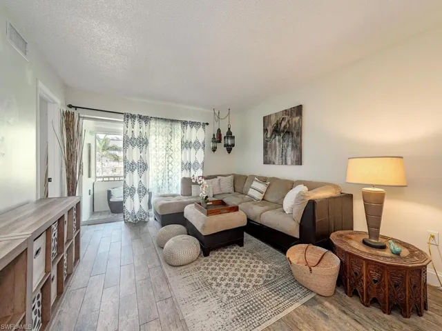 Living room with visible vents, wood finished floors, and a textured ceiling