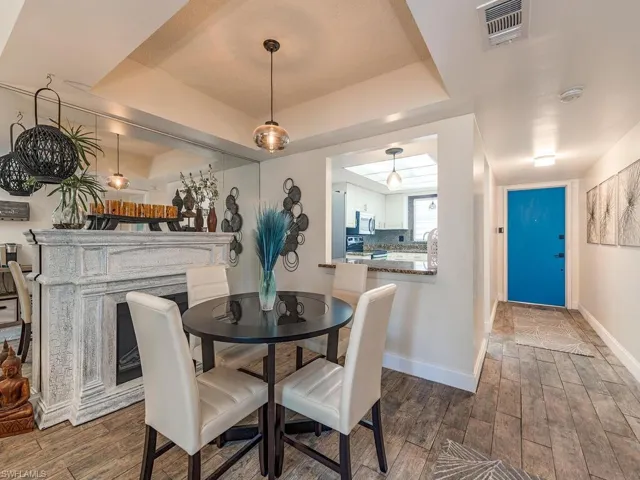 Dining room featuring a tray ceiling, baseboards, dark wood finished floors, and visible vents