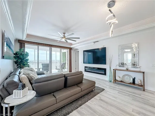 Living room featuring light hardwood -style floors, crown molding, and ceiling fan and electric fireplace