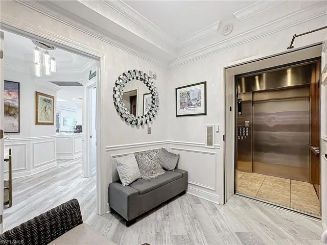 Hallway with light hardwood / wood-style floors, elevator, and ornamental molding
