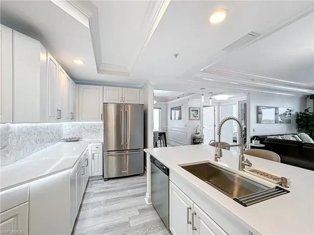 Kitchen featuring white cabinetry, crown molding, light hardwood / wood-style flooring, a tray ceiling, and appliances with stainless steel finishes