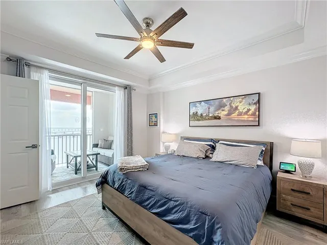 Bedroom with ornamental molding, ceiling fan, access to exterior, and a tray ceiling