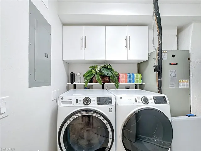 Laundry area with cabinets, washer and dryer, and electric panel